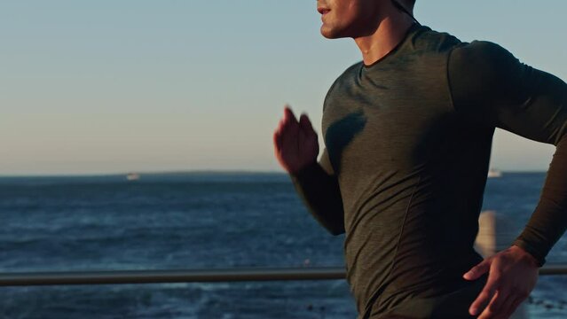 Asian man, running and earphones by beach for sunset workout, training and exercise for health, fitness and wellness. Japanese athlete, sprinting and cardio by ocean sea with music, podcast and radio