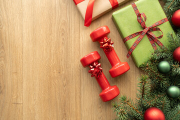 Christmas gift boxes, gym workout dumbbells, tree branches and decorations. Exercise equipment as...