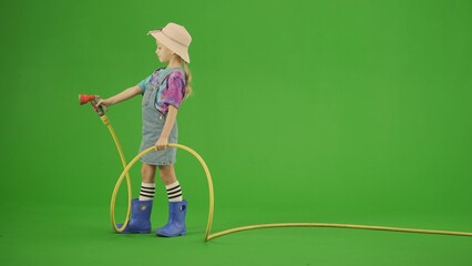 Portrait of girl in dress and rubber boots on chroma key green screen. Small cute girl gardener...