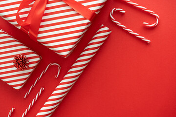 Red and white stripes wrapping paper roll, striped pattern Christmas gift boxes and candy canes decorations. Festive presents composition with copy space. Winter holiday season gift guide concept. - Powered by Adobe