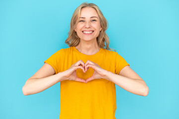 Young woman showing heart shape with fingers, feeling love