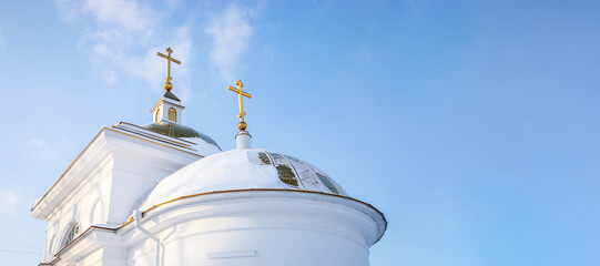 Church in Verh-Nevinsky, Russia. White snow covered domes with gold crosses against blue sky. Banner
