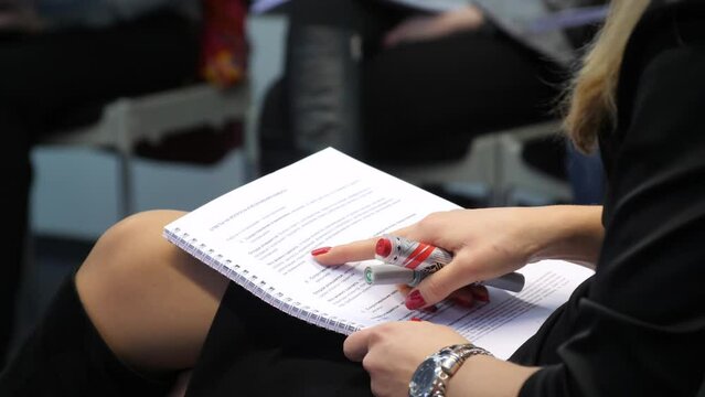 Business coach woman reading tasks sitting on chair in group of people on corporate training. Discussing project on office meeting, briefing. Team building, education, seminar or master class concept.