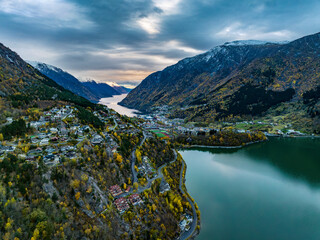 aerial view over town of odda on fjord with mountains covered with snow on background in norway - obrazy, fototapety, plakaty
