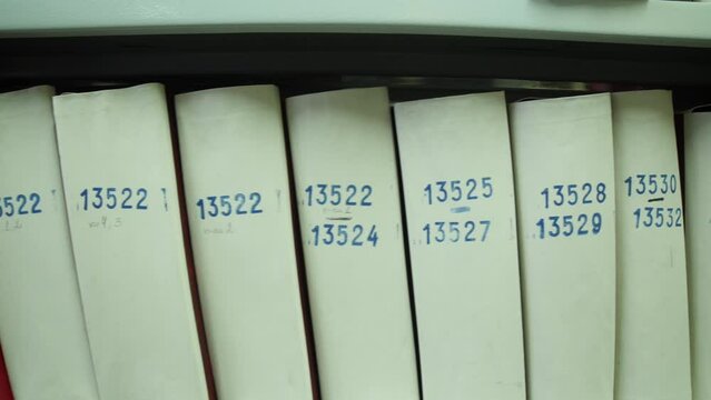Medical legal numbered documents on shelves of archive in paper folders. Green white boxes with papers. Personal files of employees workers in large company, state-owned enterprise. Storage system.