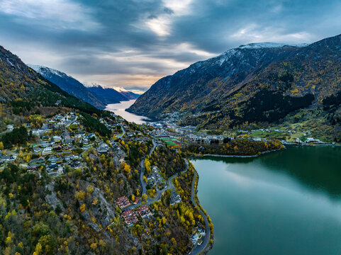 aerial view over town of odda on fjord with mountains covered with snow on background in norway