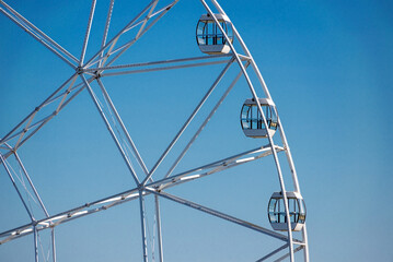 Big, tall white Ferris wheel in front of a perfect blue sky