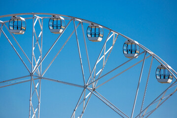 Big, tall white Ferris wheel in front of a perfect blue sky