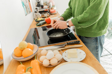 Cropped view of man holding egg near frying pan while cooking breakfast  in morning