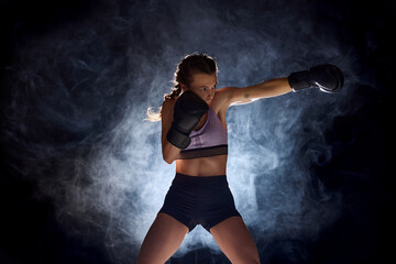 Dynamic and intense, female professional boxer showcases her athleticism against black studio...