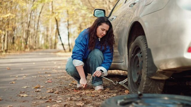 Roadside Resilience: Woman Changing Flat Tire During Journey, Roadside Breakdown. High quality 4k footage