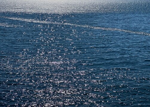 Blue sea water glittering silvery surface.