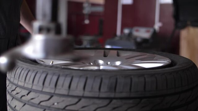 Repairman clamp wheel disk in fitting machine to remove rubber tire.