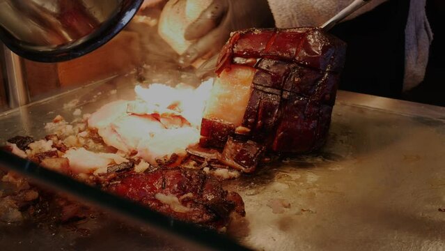 Preparing sandwich with freshly cooked glazed ham on market 