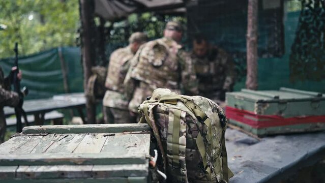 Shot Focused on Backpack and Ammo Boxes, Commander and Soldiers in Background
