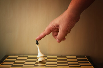 The index finger overturns the chess king on the chessboard. Admitting defeat in the game, loss in...