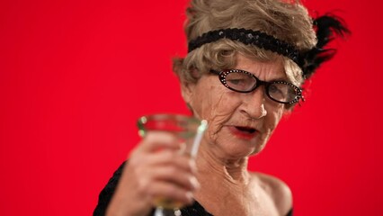Closeup funny portrait of happy elderly toothless elderly old woman wearing glasses pointing fingers herself ask say who me, smiling talking and pointing. Isolated on red background.