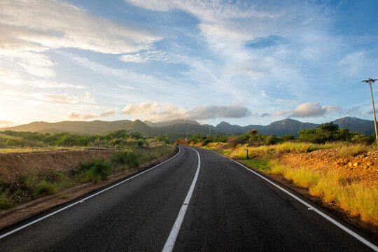 Sunrise in the desert. Tour of a desert island, full of xeric vegetation. Cactus and red earth. Mountains, clouds and sun