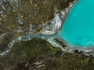 An aerial view of the blue water of the mountain lake of the Briksdalsbreen Glacier transforming into a river