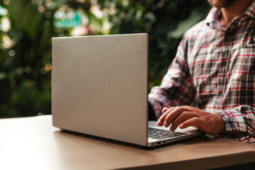 A young man works on a gray laptop. A freelancer works online in a coworking space. Student...