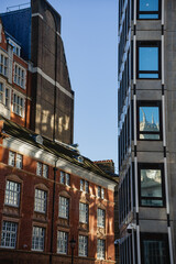 Brick and cement buildings with different styles of windows against the sky in London.