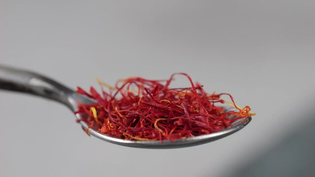 Dried crimson saffron on metall spoon close-up. Orange red spice for food. Crocus sativus flower saffron
