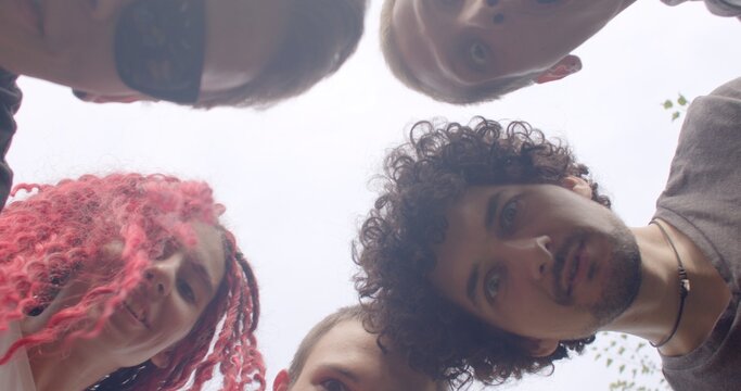 Group of young people discovering something in the grass. Lost item. One of them lost a personal item, like a phone or a piece of jewelry, and they are trying to locate it. Geocaching game hunting.