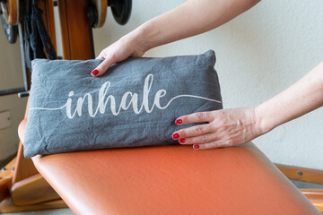 female hands holding small pillow that says inhale on training bed