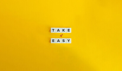 Take It Easy Phrase. Block Letter Tiles on Yellow Background. Minimalist Aesthetics. - obrazy, fototapety, plakaty