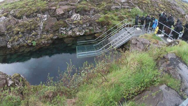 Thingvellir National Park, Iceland - June 26, 2023: Tourists prepare to snorkel between the two tectonic plates at the steps to enter the cold waters of Silfra.