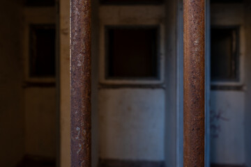 Close-up of the interview booth of an old prison framed by iron bars. This striking image relates to themes of incarceration and freedom, border security, refugee influx. 