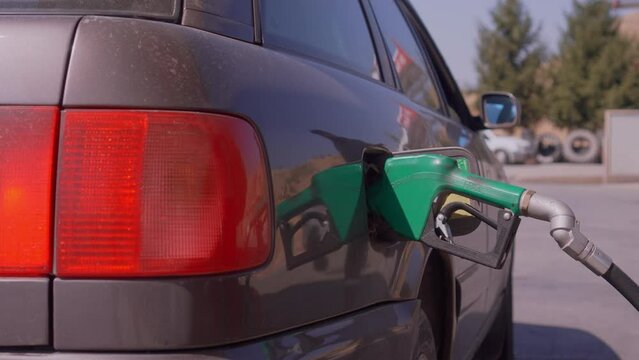 Close-up shot: refueling nozzle inserted into fuel neck of car while refueling car at gas station. Refueling, Energy and Transportation Concept.