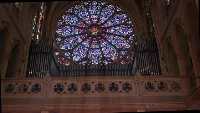 Historic church organ under a grand stained-glass window.