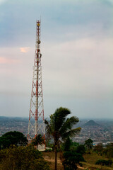 Telecommunication tower on the hill with cloudy sky background