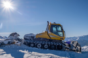 Snow removal equipment. Snowcat in the mountains against the blue sky.