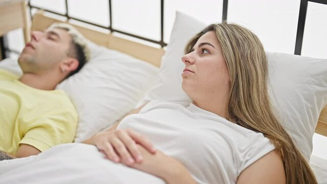 Beautiful couple covering ears for snore lying on bed at bedroom