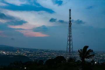 Telecommunication tower and cityscape at twilight,