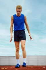 Focused runner propelling forward with intent. Young athlete man, professional sportsman warming-up...