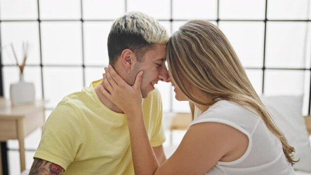 Beautiful couple sitting on bed touching nose at bedroom