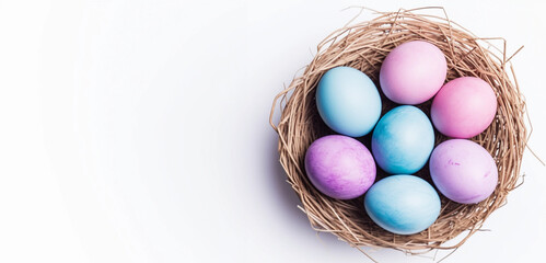 Pastel pink and blue Easter eggs in a nest on the white background with copy space. Top view spring backdrop.