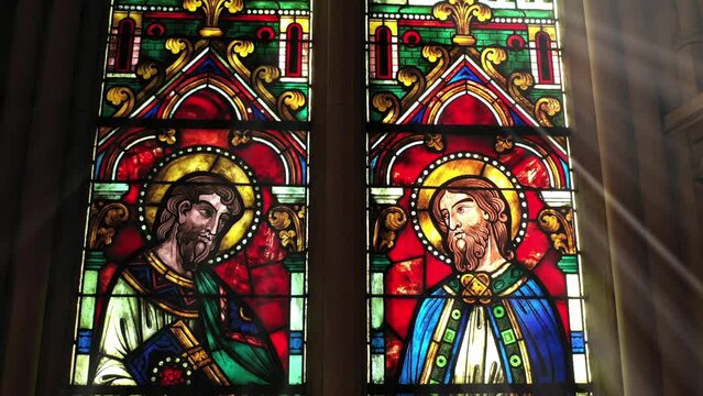 Stained glass saints with halos in solemn grace.