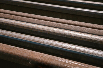 Many used rusty rails of different length stored at a ground for old rails replacement. Diagonal placement close up photo