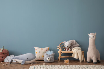 Warm and cozy living room interior with blue wall, rattan sideboard, stylish armchair, plush whale,...