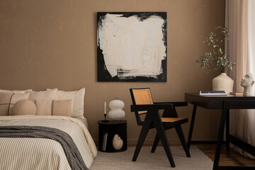 Cozy composition of warm bedroom interior with mock up poster frame, bed, gray bedding, black desk, ratan chair, vase with leaves, beige carpet and personal accessories. Home decor. Template.