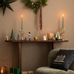 Aesthetic composition of christmas living room interior with green armchair, wooden bench, pillows,...