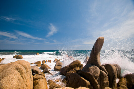 Blue water splashing against rocks on the beach on the Cote d'Azure; French Riviera, France