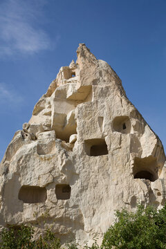 Close-up of Cave Houses carved into pointed rock formations against a bright blue sky near the town of Goreme in Pigeon Valley, Cappadocia Region; Nevsehir Province, Turkey