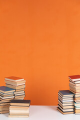 Lots of stacks of old educational books on orange background University School Library