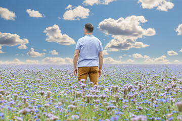 A happy man on a background of wildflowers. Cloudy sky. Environment and landscape
