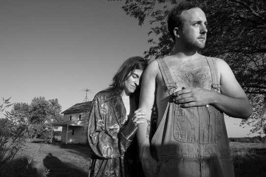 Man and woman stand outside an old house, woman leaning her head on the man's arm; Bennet, Nebraska, United States of America